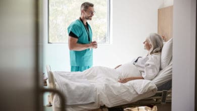 Surgeon Visiting And Talking With Mature Female Patient In Hospital Bed