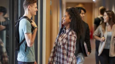 Group Of College Students Walking Through College Corridor